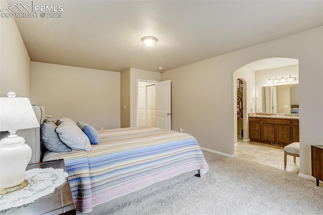 7567 Black Spruce Hts, Colorado Springs, CO 80908 - bedroom with arched walkways, light carpet, baseboards, ensuite bathroom, and a closet