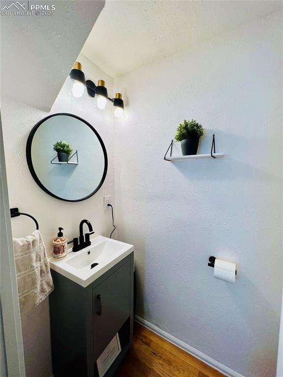 313 E Evans Ave, Pueblo, CO 81004 - bathroom featuring wood finished floors, vanity, and baseboards