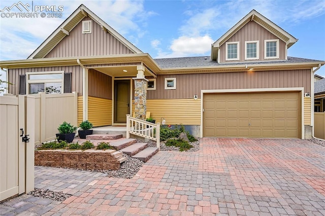 6016 Haster Grv, Colorado Springs, CO 80927 - view of front of home featuring decorative driveway, fence, a garage, roof with shingles, and board and batten siding