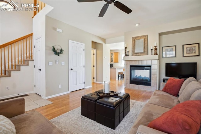 living area featuring ceiling fan, wood finished floors, a fireplace, stairway, and baseboards