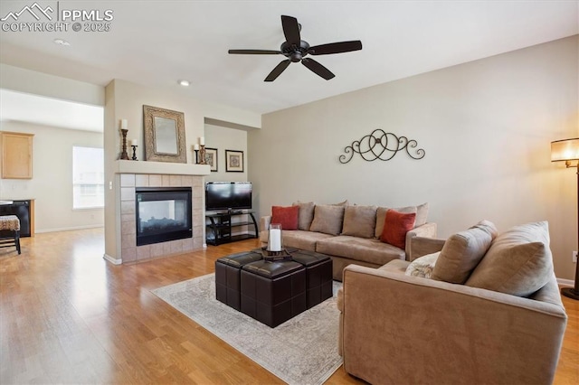 living area with light wood finished floors, a tiled fireplace, ceiling fan, recessed lighting, and baseboards