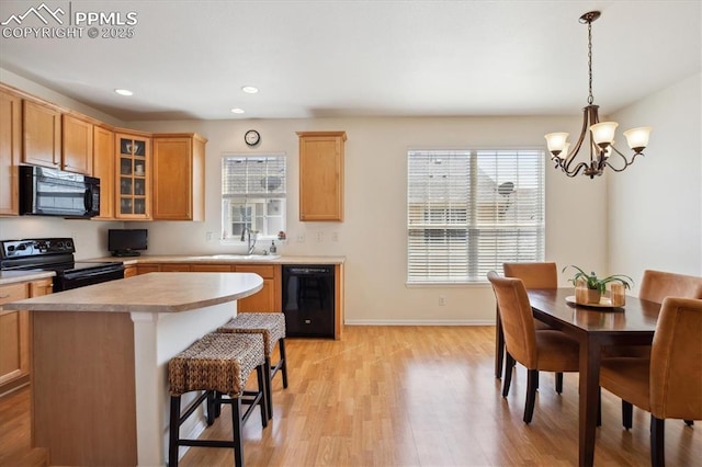 kitchen with black appliances, light countertops, light wood-style floors, recessed lighting, and glass insert cabinets
