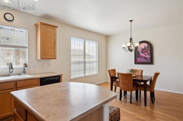 kitchen with a sink, dishwasher, a chandelier, light wood-style floors, and a center island