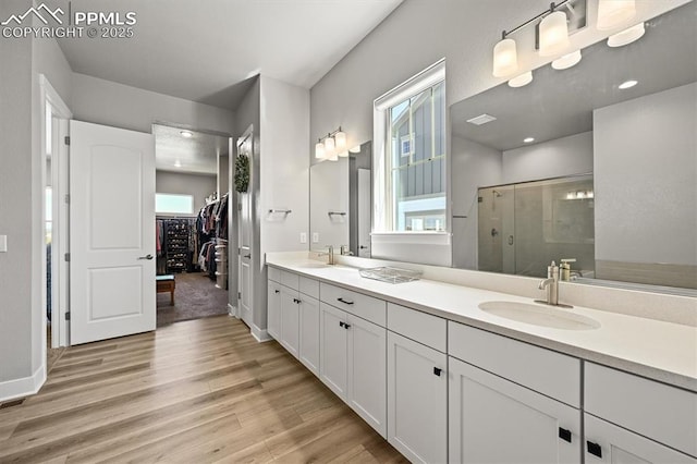 3293 Offbeaten Pl, Castle Rock, CO 80108 - bathroom featuring wood finished floors, a stall shower, a spacious closet, double vanity, and baseboards