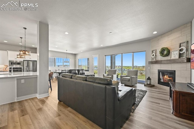 3293 Offbeaten Pl, Castle Rock, CO 80108 - living room featuring a tiled fireplace, light wood finished floors, recessed lighting, and a textured ceiling