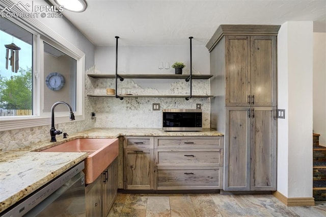 kitchen featuring open shelves, stainless steel appliances, a sink, backsplash, and light stone countertops