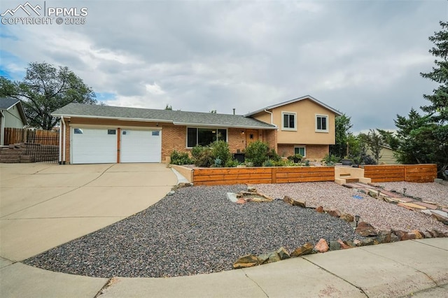 tri-level home featuring driveway, fence, an attached garage, and brick siding