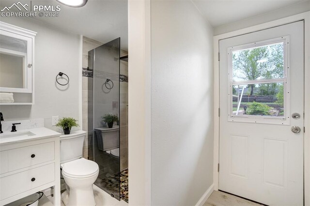 bathroom with a stall shower, vanity, toilet, and baseboards