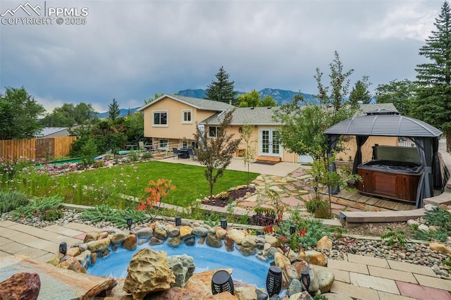 view of yard with a hot tub, a patio area, french doors, a gazebo, and a mountain view