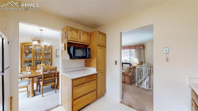 4012 Maxwell Pl, Colorado Springs, CO 80909 - kitchen with black microwave, light countertops, light carpet, a chandelier, and decorative light fixtures