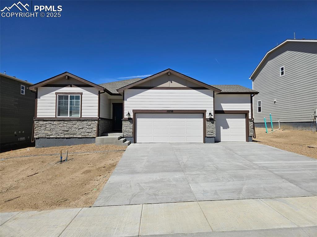 view of front of house featuring stone siding, an attached garage, and concrete driveway