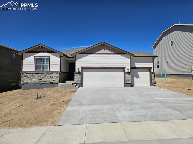 view of front of house featuring stone siding, an attached garage, and concrete driveway