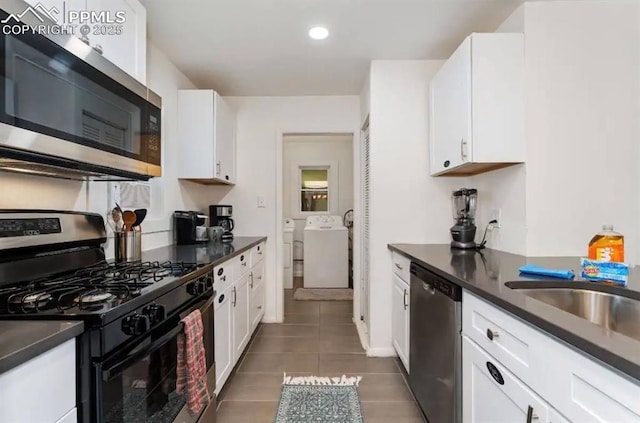 739 S Utica St, Denver, CO 80219 - kitchen featuring appliances with stainless steel finishes, separate washer and dryer, dark countertops, dark tile patterned floors, and white cabinets