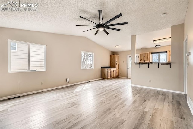 4790 Hennings Dr, Colorado Springs, CO 80911 - unfurnished living room with ceiling fan, light wood-style floors, vaulted ceiling, a textured ceiling, and baseboards