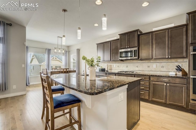 6898 Sedgerock Ln, Colorado Springs, CO 80927 - kitchen with stainless steel appliances, a kitchen bar, dark stone counters, backsplash, and dark brown cabinetry
