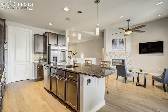 6898 Sedgerock Ln, Colorado Springs, CO 80927 - kitchen with a sink, appliances with stainless steel finishes, a kitchen breakfast bar, light wood finished floors, and dark stone countertops