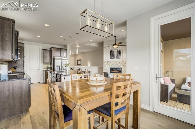 6898 Sedgerock Ln, Colorado Springs, CO 80927 - dining room with ceiling fan, light wood-style flooring, a glass covered fireplace, and recessed lighting
