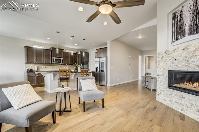 6898 Sedgerock Ln, Colorado Springs, CO 80927 - living room featuring a ceiling fan, light wood-type flooring, a stone fireplace, recessed lighting, and baseboards