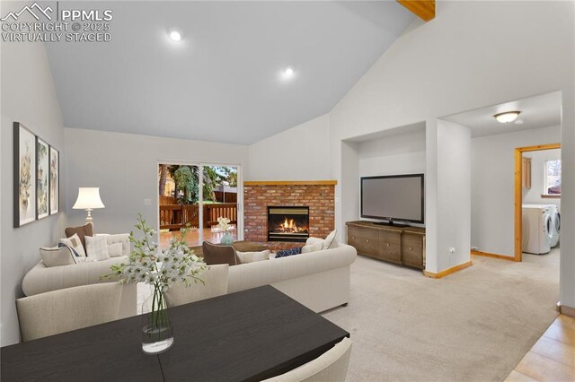 carpeted living area featuring high vaulted ceiling, washing machine and dryer, baseboards, healthy amount of natural light, and a fireplace