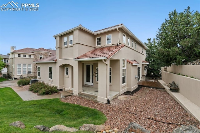 mediterranean / spanish house featuring a tile roof, stucco siding, and cooling unit
