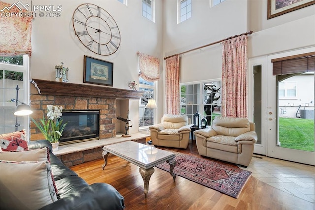 living room with a towering ceiling, a fireplace, and wood finished floors