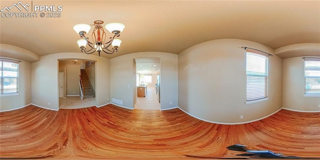 6018 Cumbre Vista Way, Colorado Springs, CO 80924 - empty room featuring arched walkways, stairway, wood finished floors, baseboards, and a chandelier