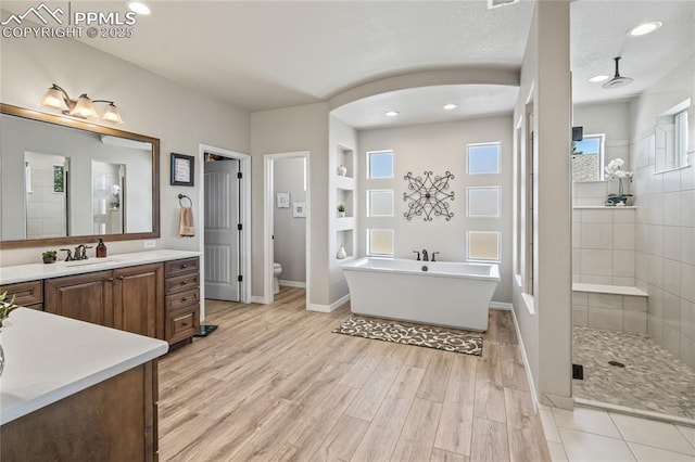 16231 Thunder Cat Way, Monument, CO 80132 - full bathroom featuring a shower stall, toilet, vanity, wood finished floors, and a soaking tub