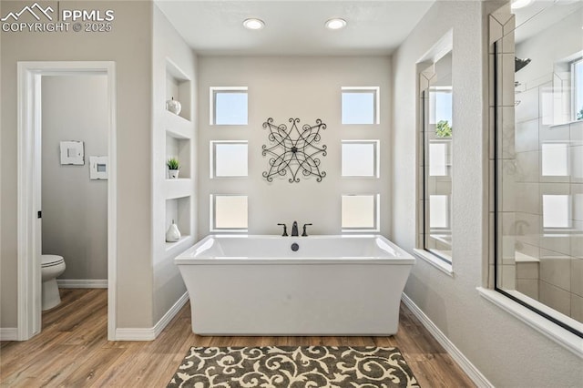 16231 Thunder Cat Way, Monument, CO 80132 - bathroom featuring wood finished floors, toilet, built in shelves, baseboards, and a freestanding tub