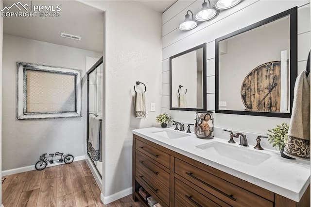16231 Thunder Cat Way, Monument, CO 80132 - bathroom with wood finished floors, a shower stall, double vanity, and baseboards