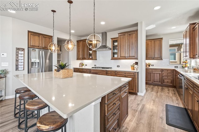 16231 Thunder Cat Way, Monument, CO 80132 - kitchen featuring appliances with stainless steel finishes, wall chimney range hood, tasteful backsplash, a breakfast bar area, and recessed lighting