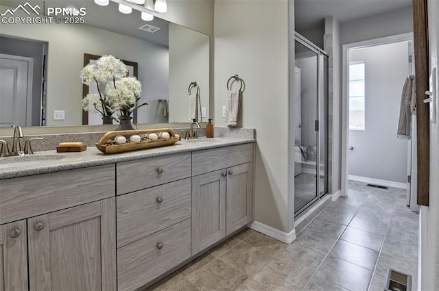 full bath featuring a shower stall, double vanity, and baseboards