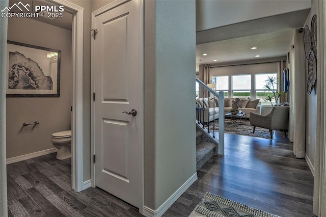 corridor featuring dark wood-style floors, baseboards, and stairs
