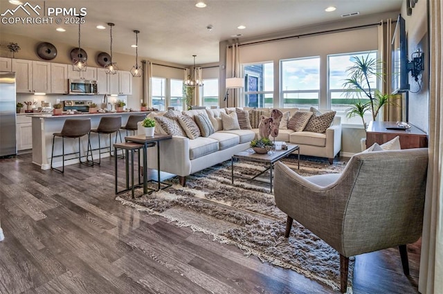living area with recessed lighting, dark wood-type flooring, and a chandelier