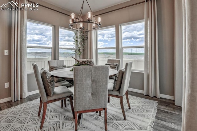 dining space featuring a chandelier, wood finished floors, and baseboards