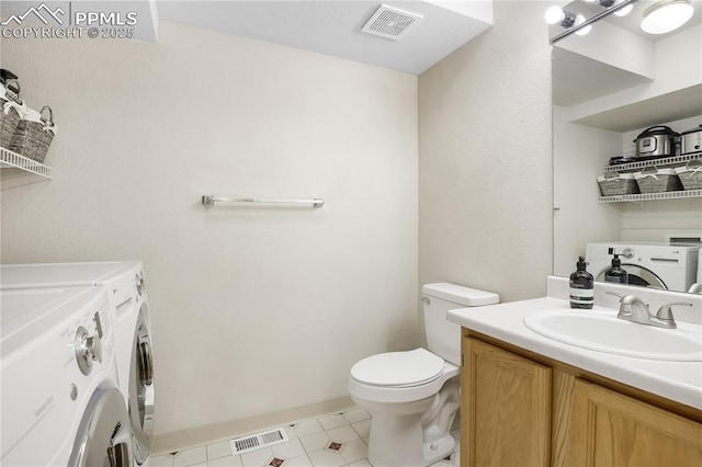 bathroom featuring independent washer and dryer, toilet, vanity, and baseboards