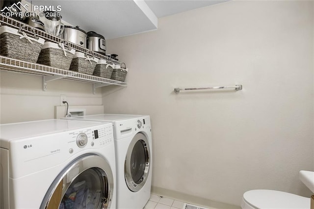 laundry area with separate washer and dryer, baseboards, and light tile patterned floors