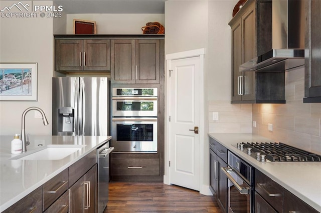 16420 Mountain Glory Dr, Monument, CO 80132 - kitchen with wall chimney exhaust hood, appliances with stainless steel finishes, a sink, dark wood-style floors, and light countertops