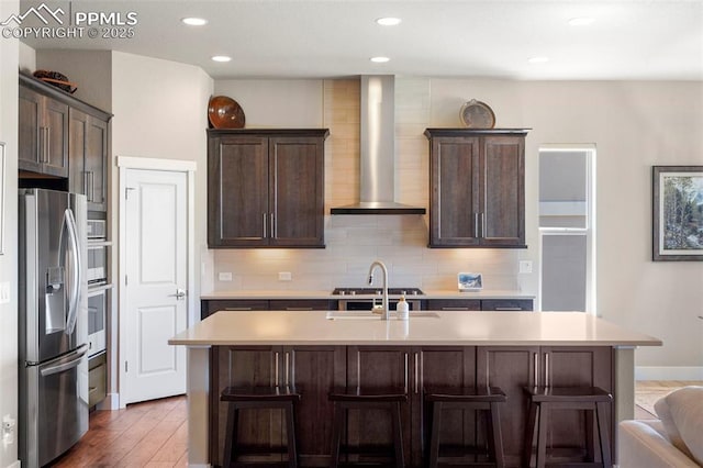 16420 Mountain Glory Dr, Monument, CO 80132 - kitchen featuring appliances with stainless steel finishes, wall chimney exhaust hood, light countertops, tasteful backsplash, and dark brown cabinets
