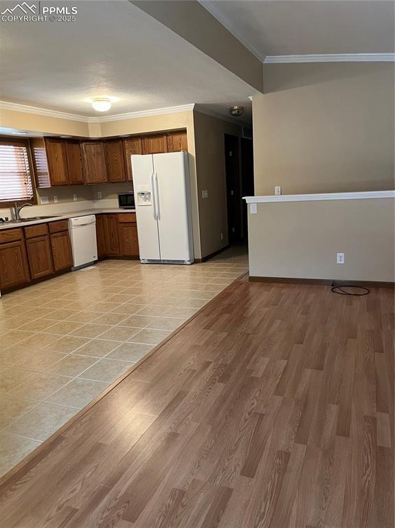 321 Aspen St, Cripple Creek, CO 80813 - kitchen featuring white appliances, a sink, crown molding, light countertops, and light wood-style floors