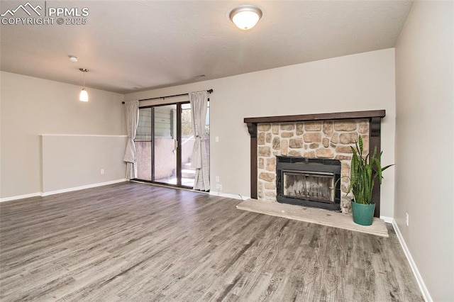 124 W Rockrimmon Blvd Unit 103, Colorado Springs, CO 80919 - unfurnished living room featuring wood finished floors, baseboards, and a stone fireplace