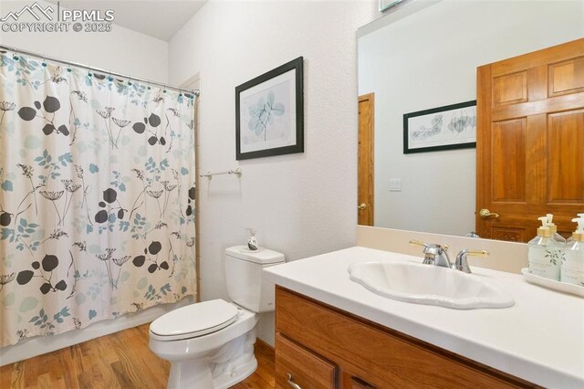 17575 Minglewood Trl, Monument, CO 80132 - bathroom with vanity, toilet, wood finished floors, and shower / tub combo