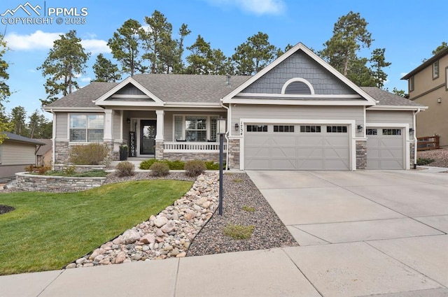 craftsman inspired home with an attached garage, covered porch, stone siding, a front lawn, and driveway