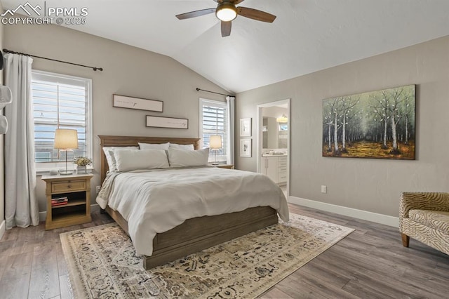 bedroom featuring vaulted ceiling, wood finished floors, baseboards, ensuite bath, and a ceiling fan