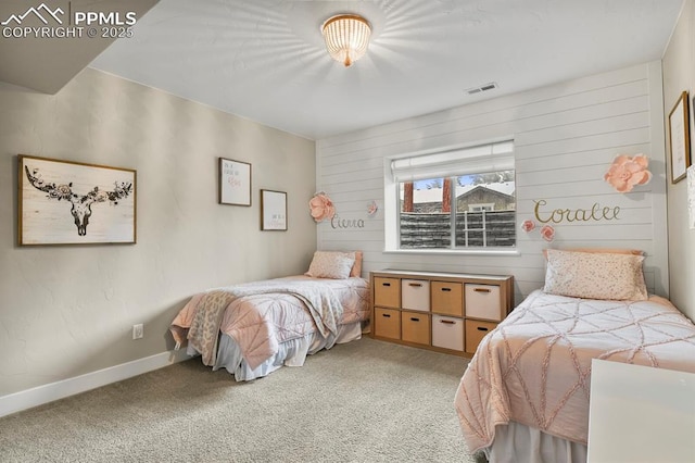 bedroom with light colored carpet, baseboards, and wood walls