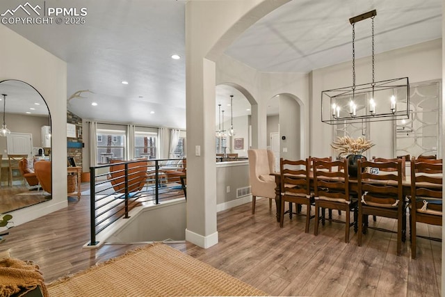 dining area featuring a chandelier, wood finished floors, arched walkways, baseboards, and recessed lighting