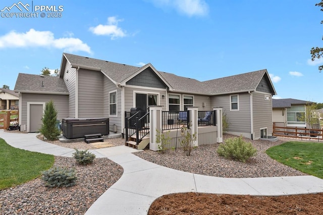 view of front of property with a hot tub, fence, a deck, and a shingled roof