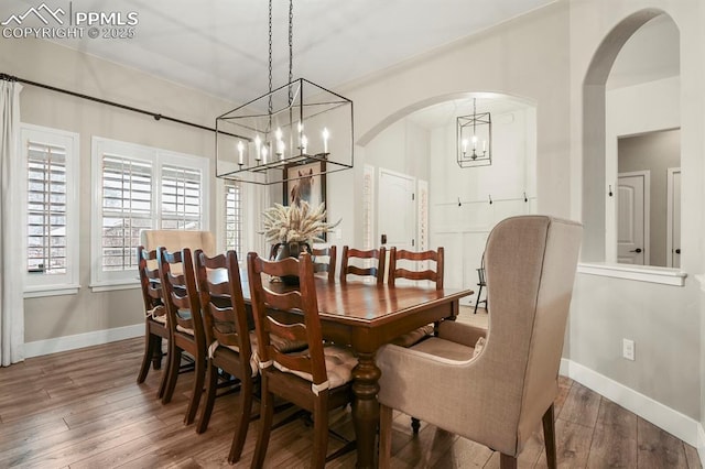 dining room featuring a chandelier, wood-type flooring, arched walkways, and baseboards