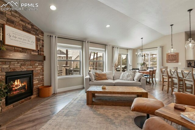 living room with vaulted ceiling, wood finished floors, a chandelier, a large fireplace, and recessed lighting
