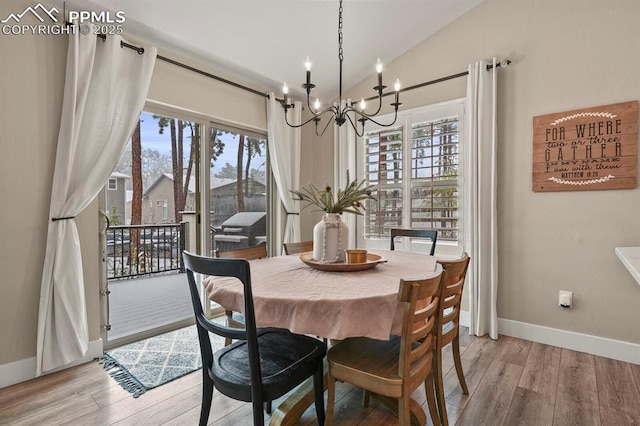 dining room with a chandelier, baseboards, light wood finished floors, and lofted ceiling