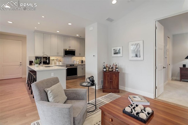 living area featuring baseboards, recessed lighting, and light wood-style floors